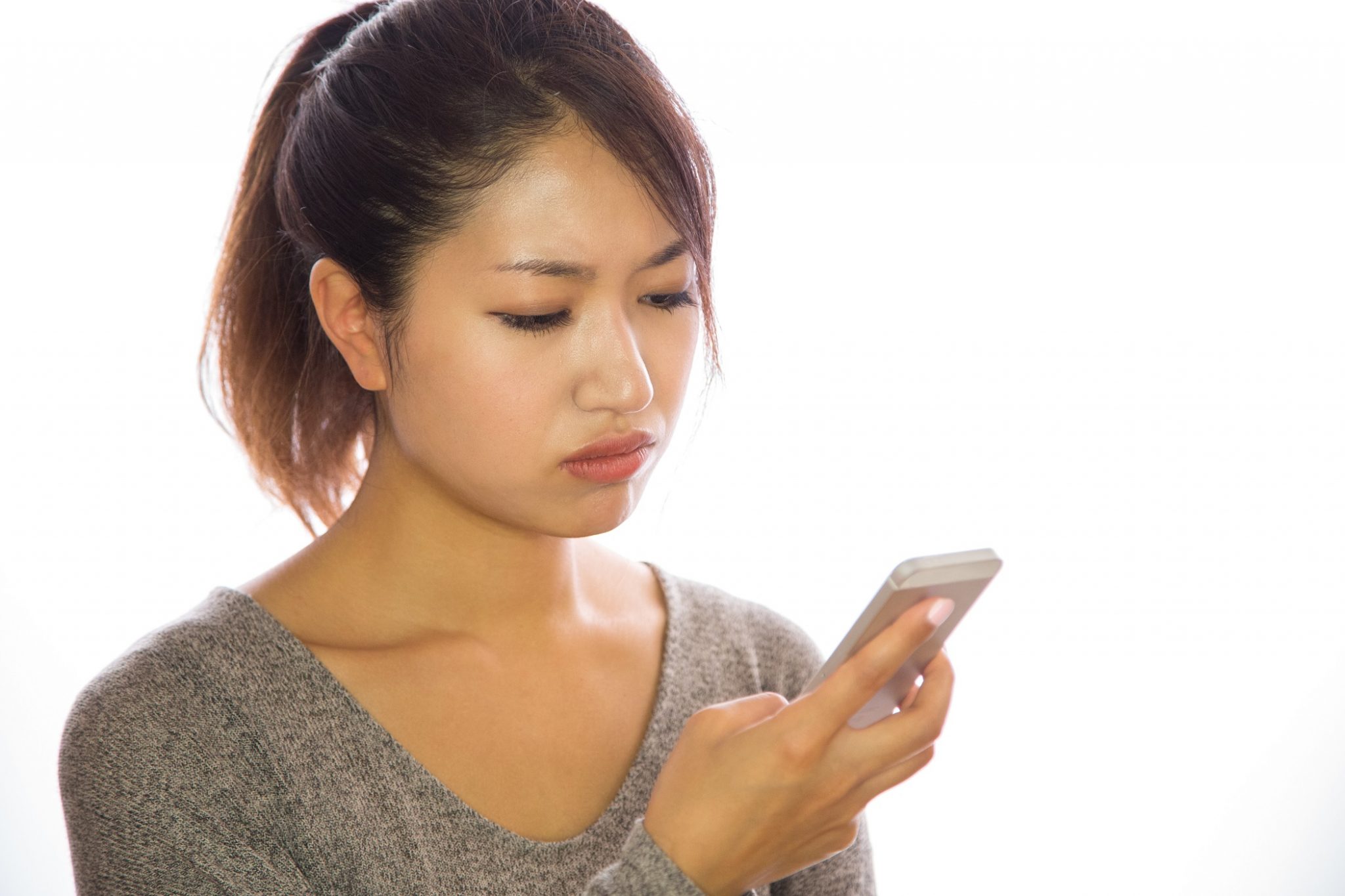 Asian young woman looking at cellphone angry