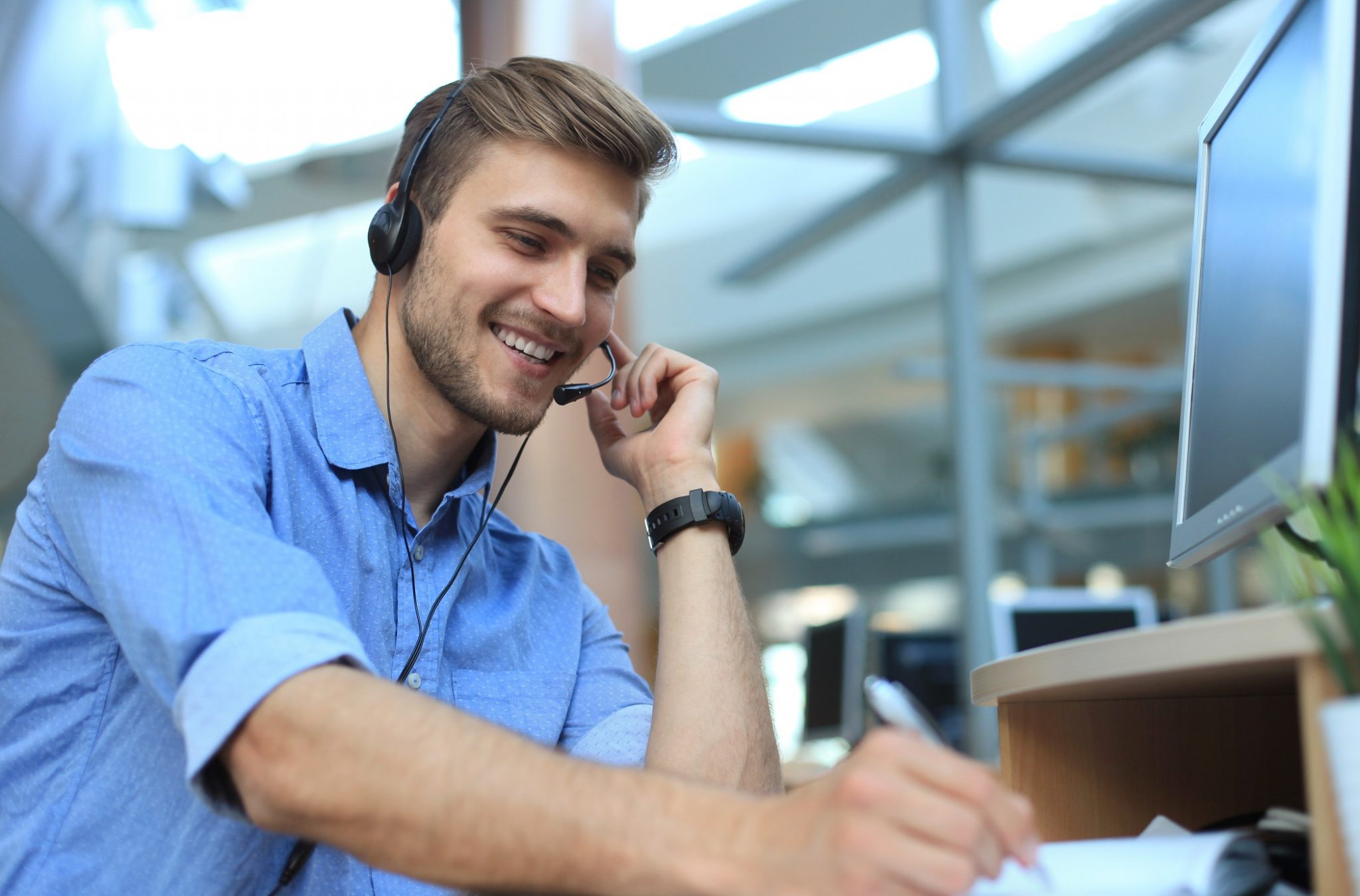 Smiling friendly handsome young male call centre operator.