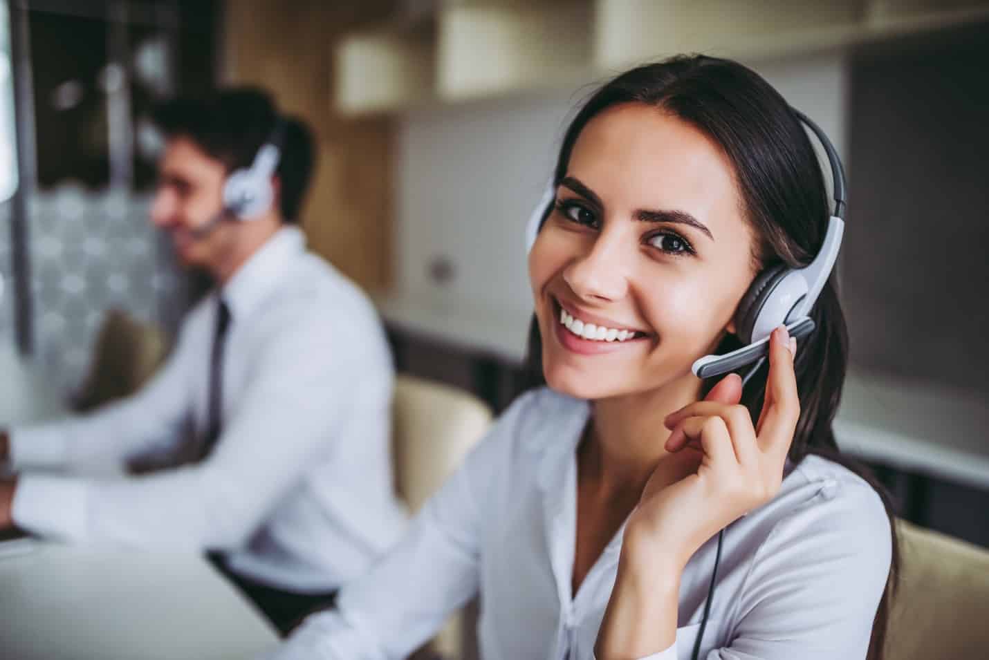 Beautiful call center workers in headphones are working at modern office.