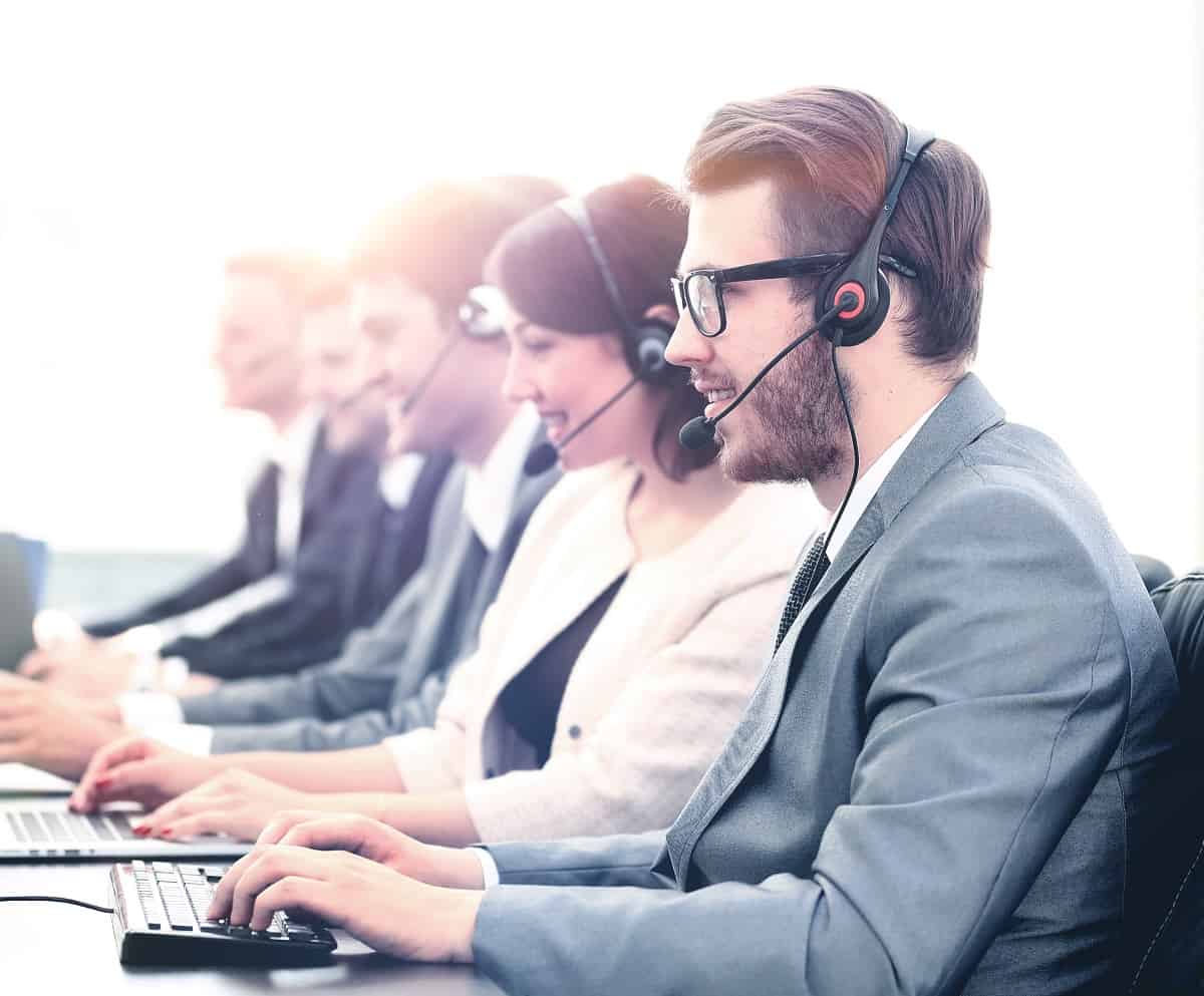 Attractive young man working in a call center with his colleagues