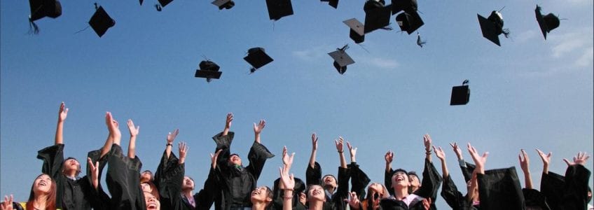 Students throwing graduation hats in the air celebrating