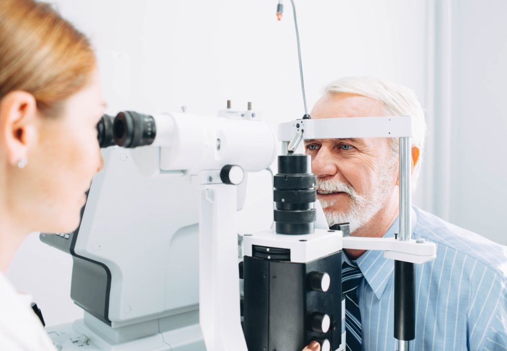optometrist checking a patient's eyes while his answering service handles phone calls