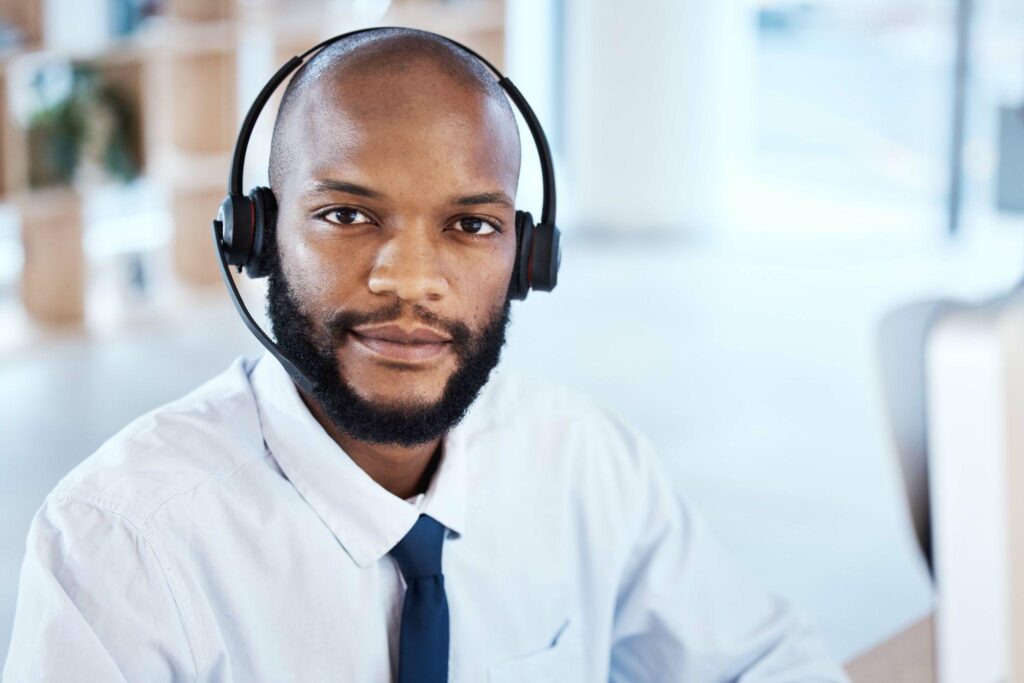 Male answering service representative wearing a white shirt and blue tie with black headset on.