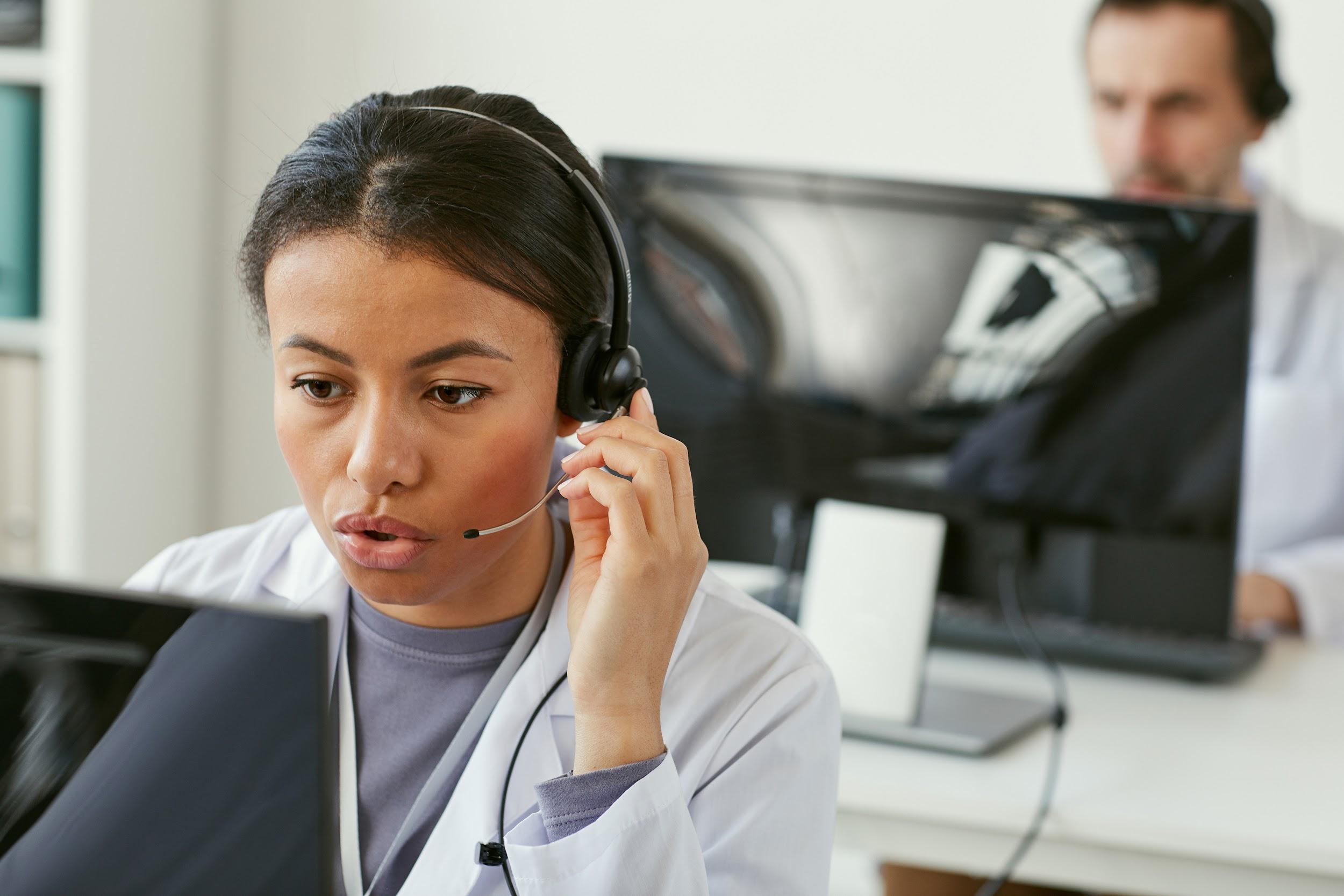Young woman wearing headphones working on computer she answering on phone calls