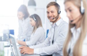 Call center worker with headset accompanied by his team.