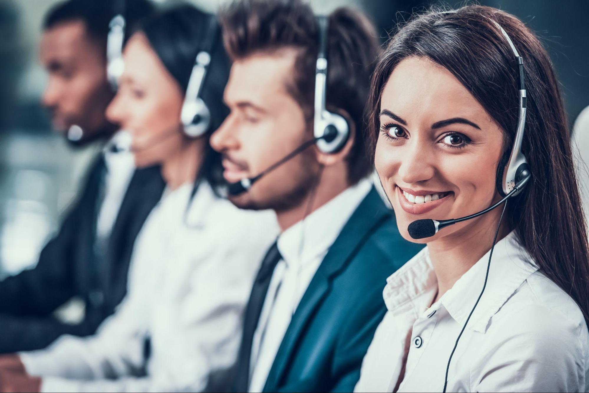 Multicultural young happy employees in call center sitting at computers and working.