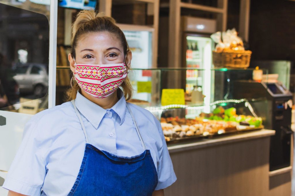 waitress with a face mask at the entrance of the cafeteria