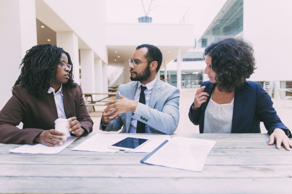 Business man and women sitting at table with papers and talking.