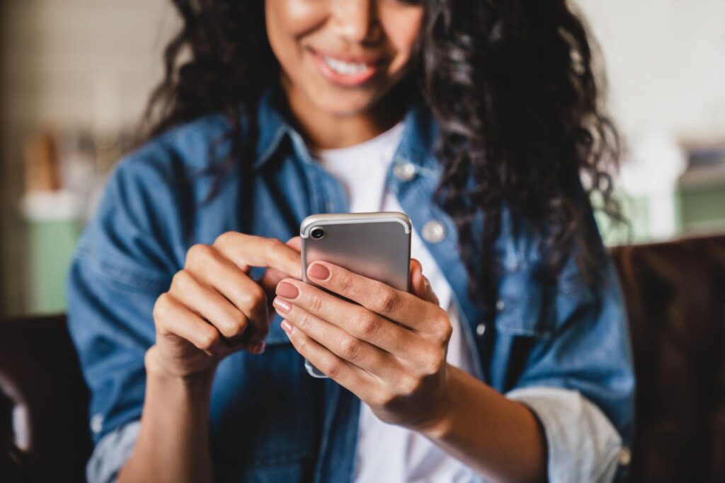 Smiling african american woman using smartphone at home
