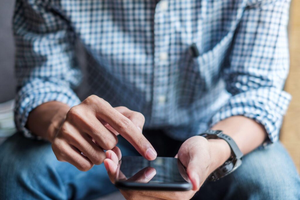 Young casual Businessman holding and using smartphone