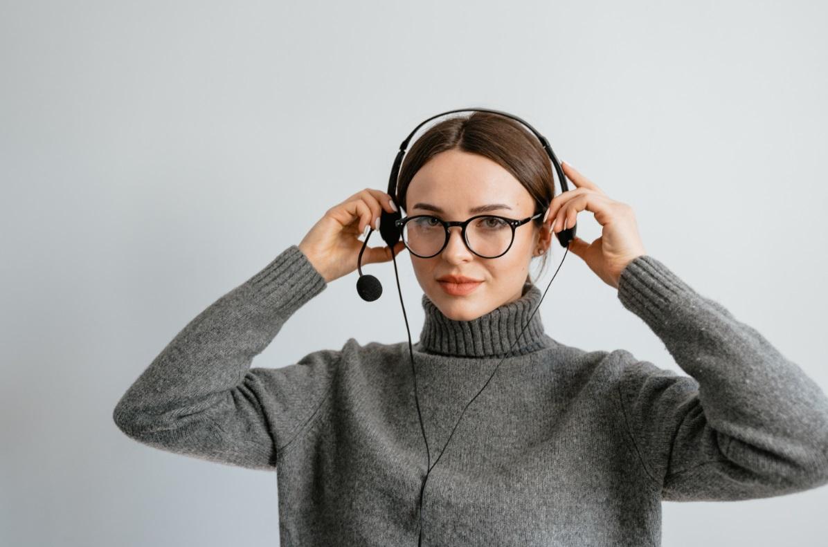 Female customer service agent with headset and gray sweater.