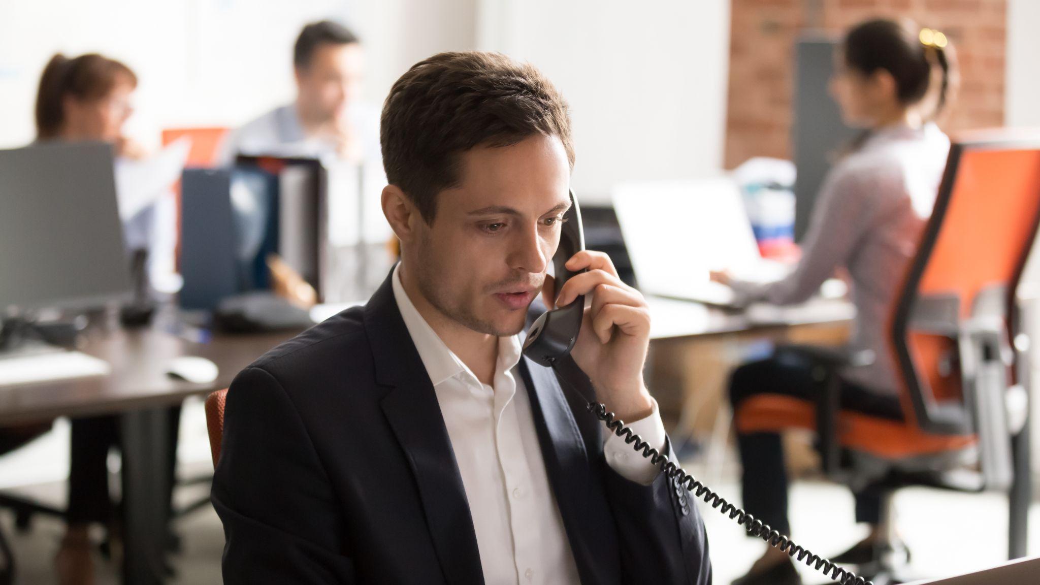 A focused man answers a business call, reflecting professional phone etiquette.