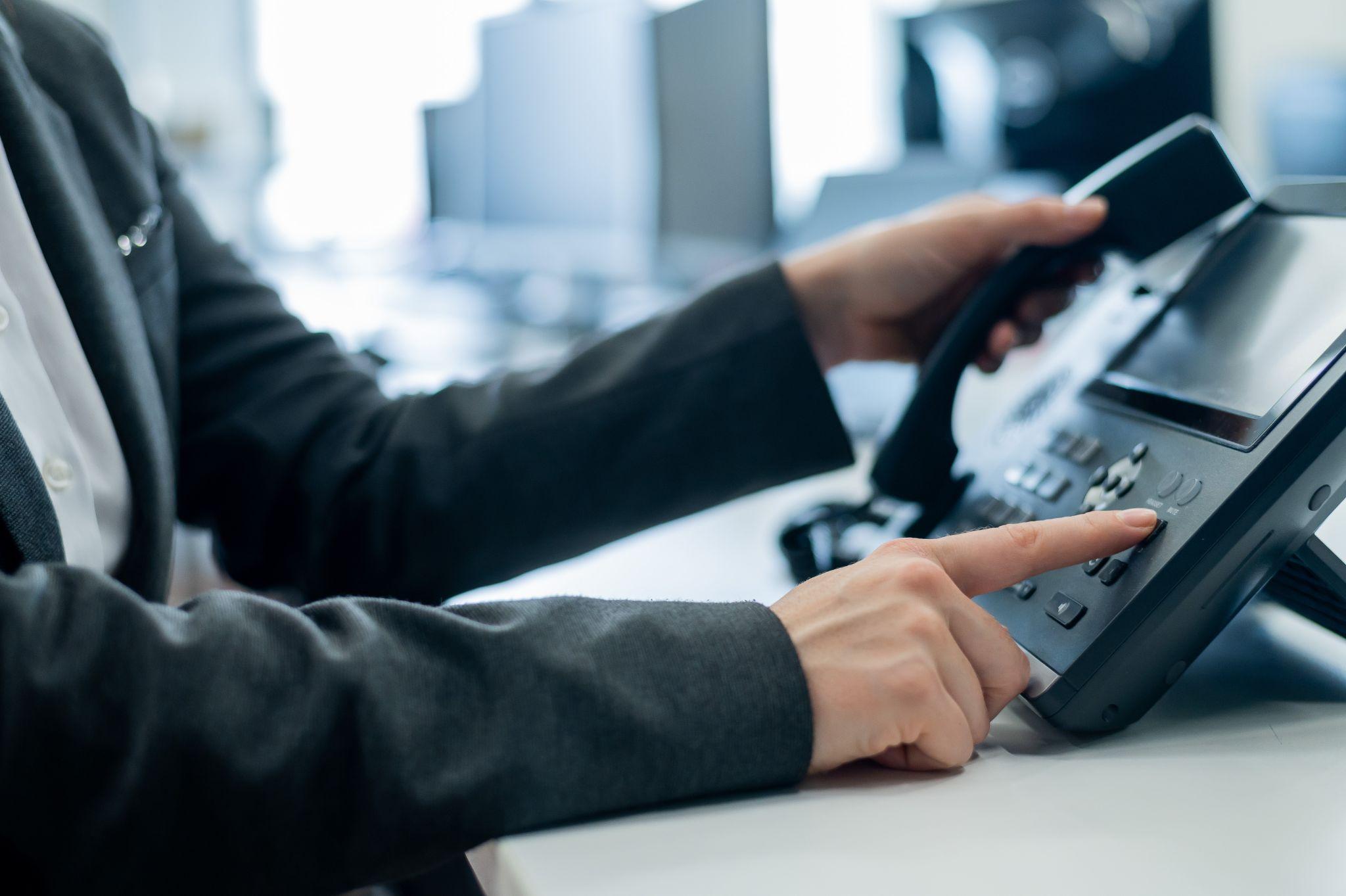 A receptionists is answering a business call on an office telephone.