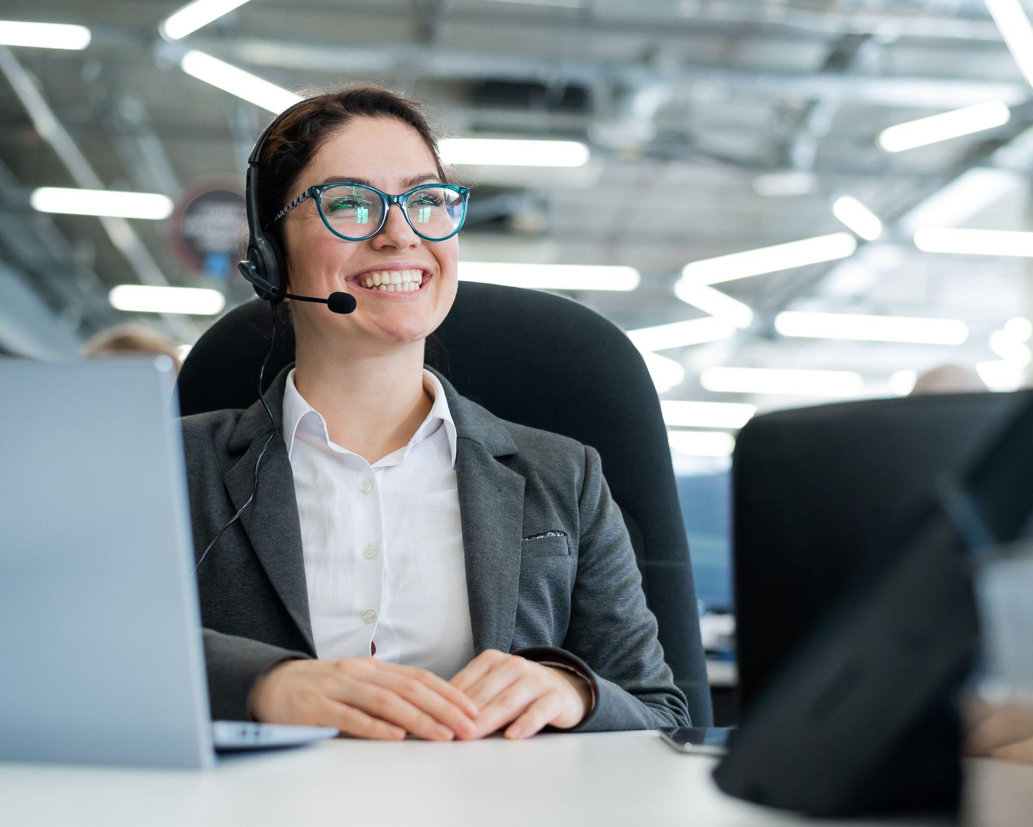 A woman receptionist wearing a headset and answering business calls.
