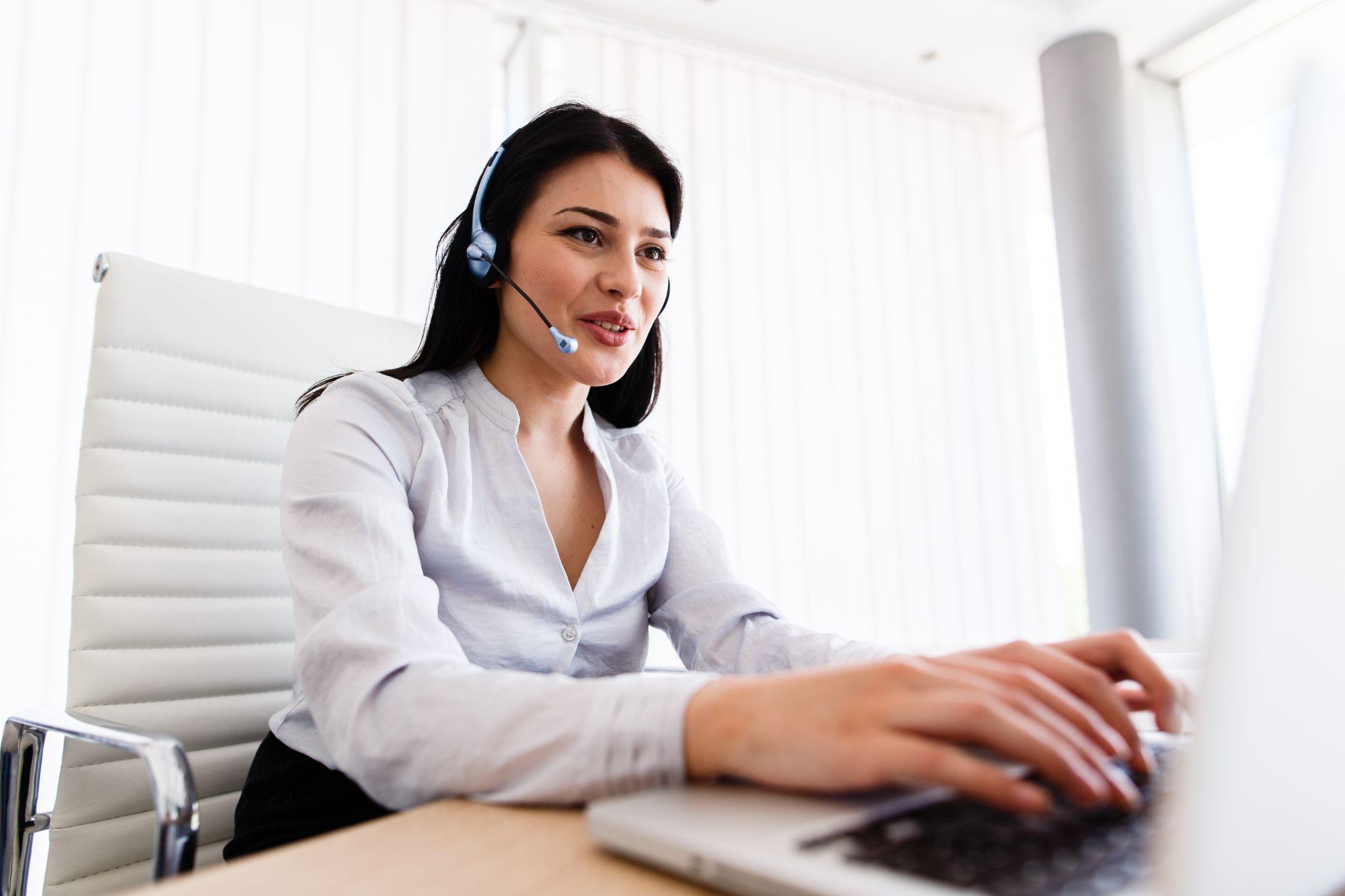 A cheerful receptionist in a headset, representing professional phone support.