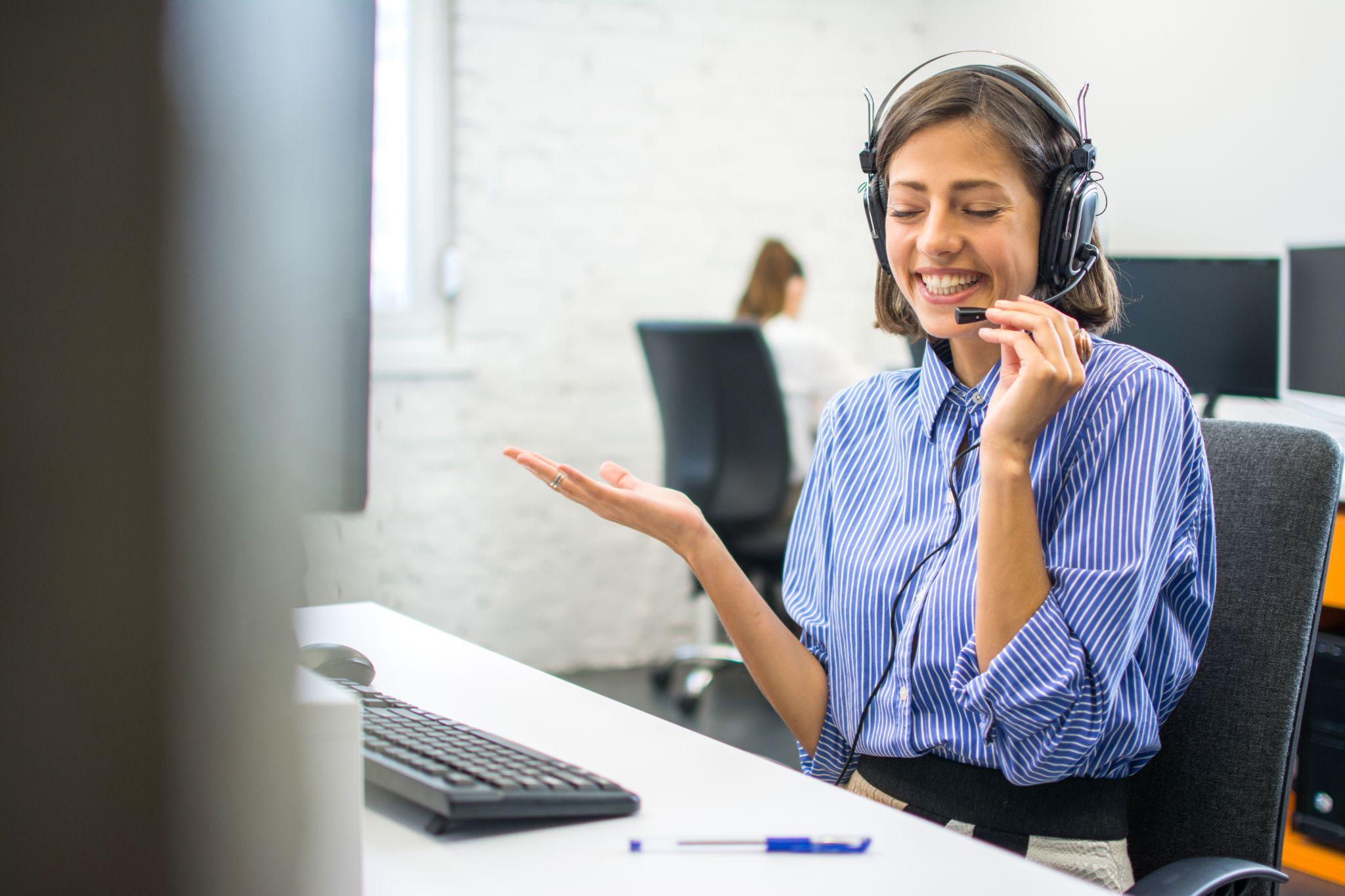 A female agent uses a headset while answering the phone, displaying strong phone call etiquette.
