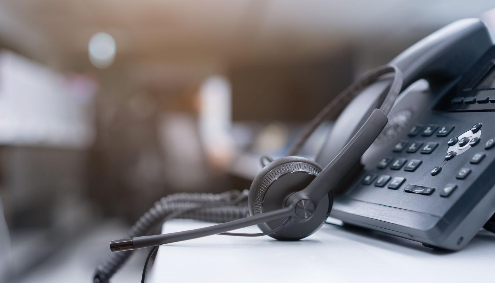 Close up black headset with telephone in operation room to communicate with vendor or client for call center and hotline service concept.