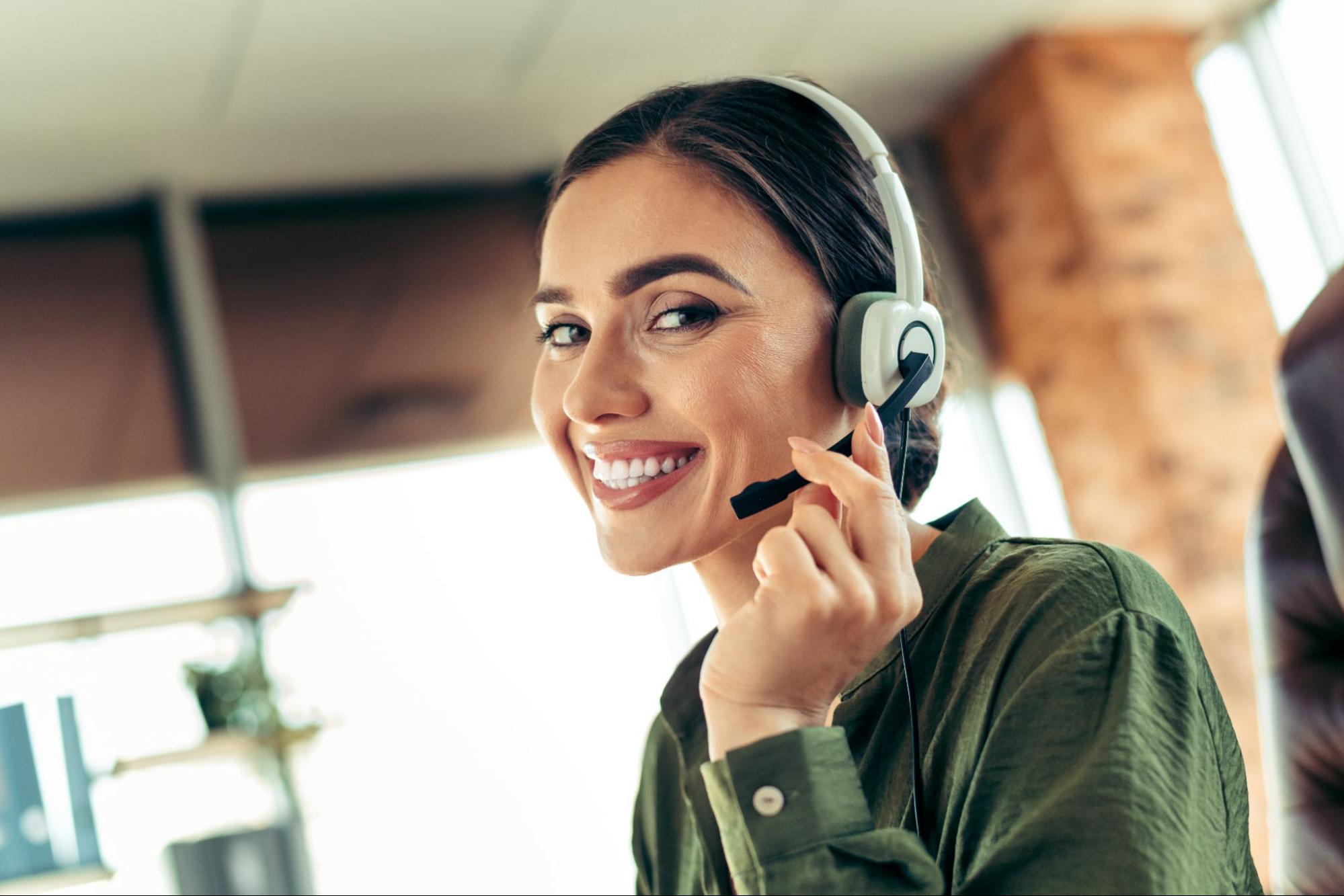 Confident businesswoman with headset working in a modern office environment with a cheerful and professional demeanor.